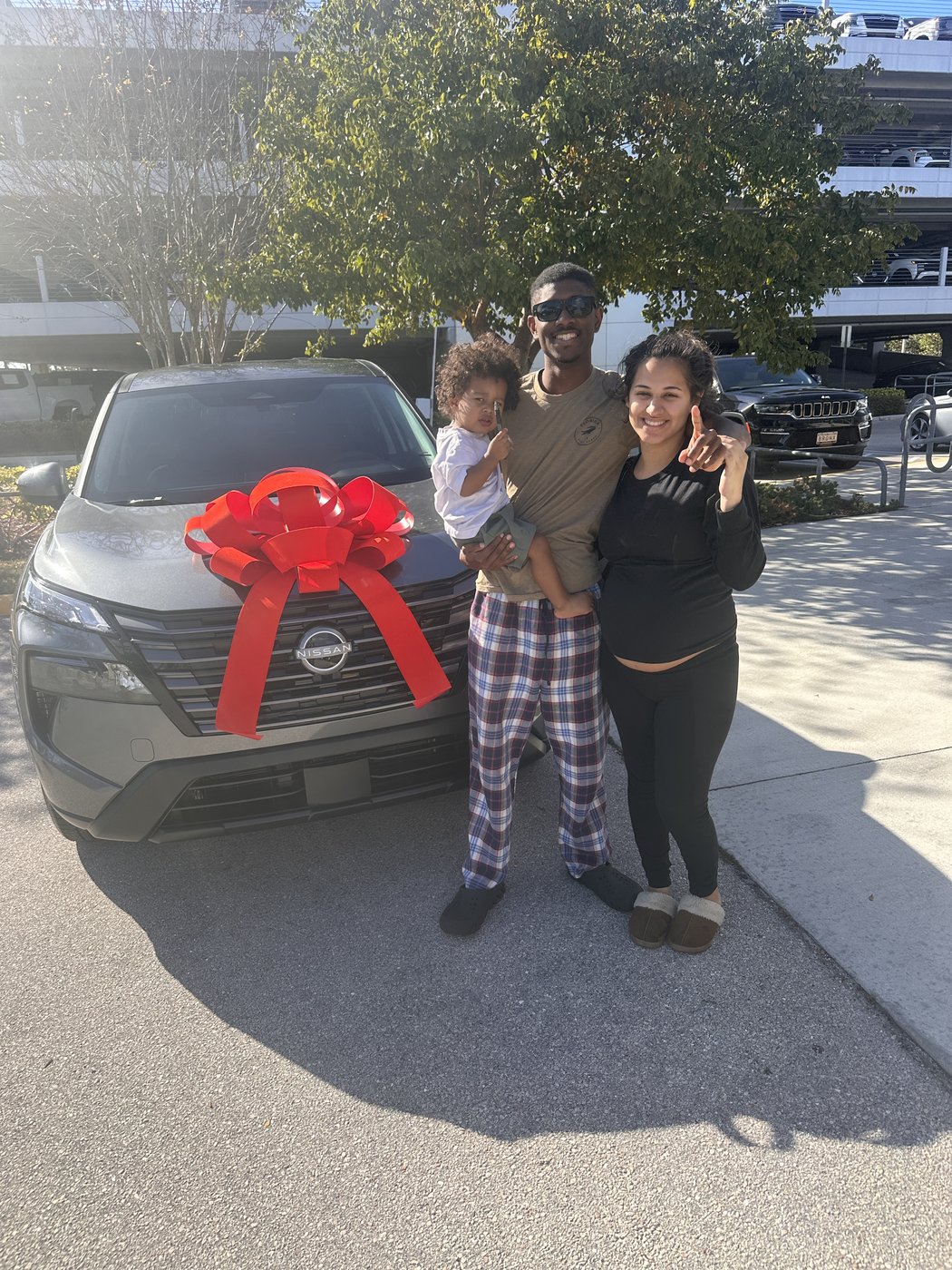 Young family with baby celebrating their new Nissan Rogue