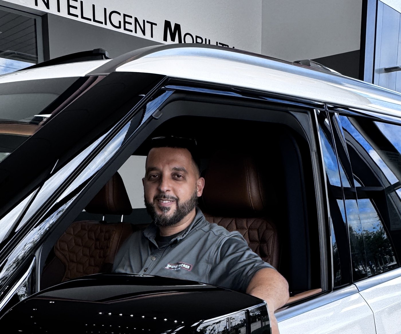 Mo Awad, car sales consultant in Palm Beach County, sitting in the driver seat of a white Nissan at the Palm Beach Nissan dealership